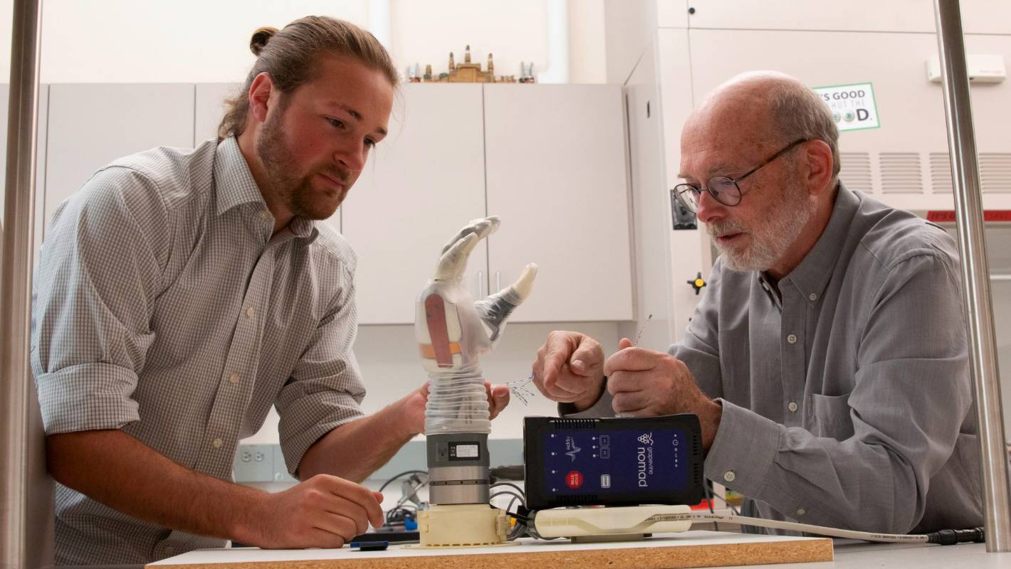 Doctoral student Jacob George, left, and professor Greg Clark examine the LUKE arm, a motorized and sensorized prosthetic that has been in development for more than 15 years